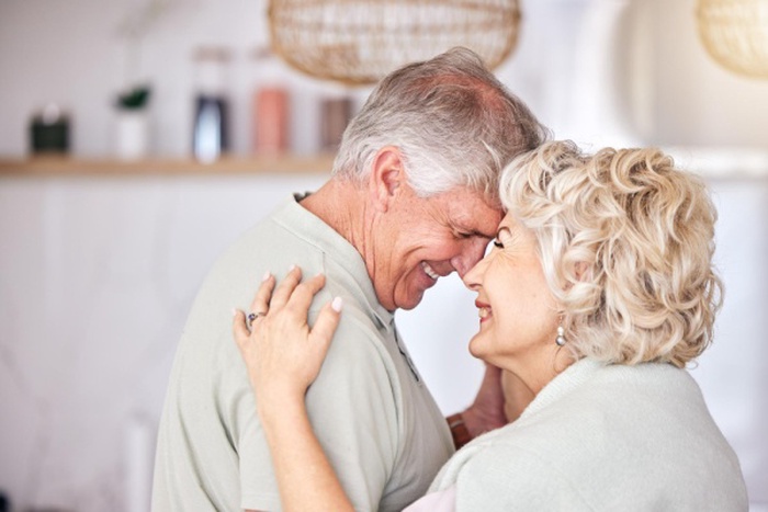 Happy love and face of senior couple dance at home with trust care and security bond and laugh retirement romance and excited man elderly man with woman hug with intimacy support or security