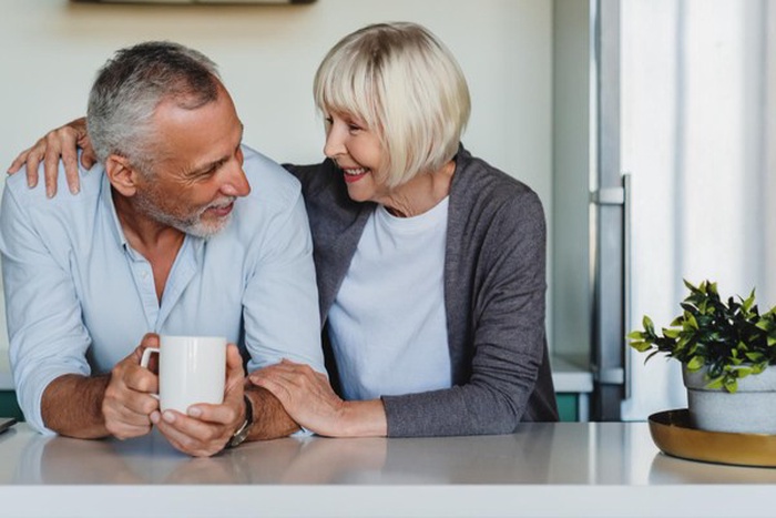 Mature woman hugging her husband at home kitchen