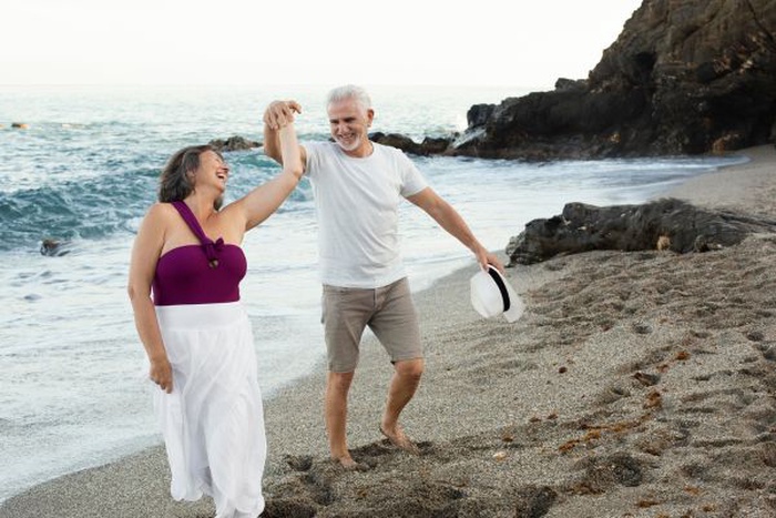 Pareja de adultos mayores bailando juntos en la playa de Carlsbad, California, disfrutando de un momento alegre y conexión mutua.