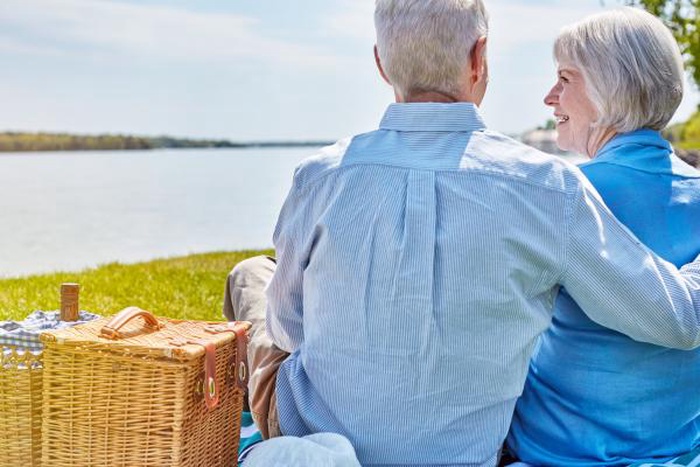 Senior couple lakeside picnic romantic retirement companionship outdoor lifestyle
