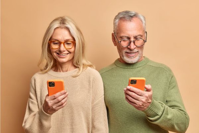 Happy senior couple using the easiest dating app for seniors on a smartphone to find local matches
