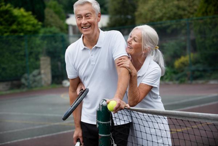 Cheerful aged pair enjoy tennis date after matching on 50+ mature singles dating site across USA