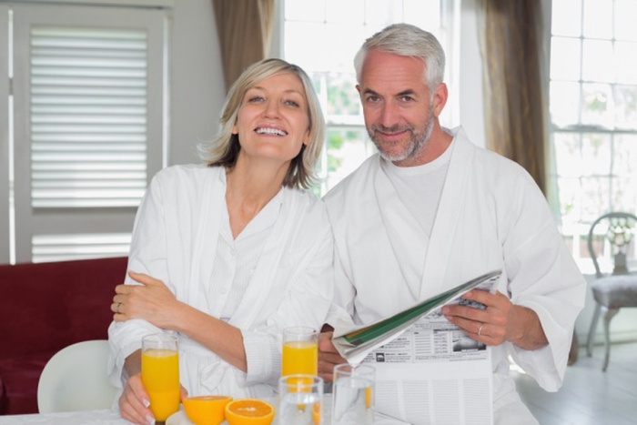 Couple reading newspaper while having breakfast