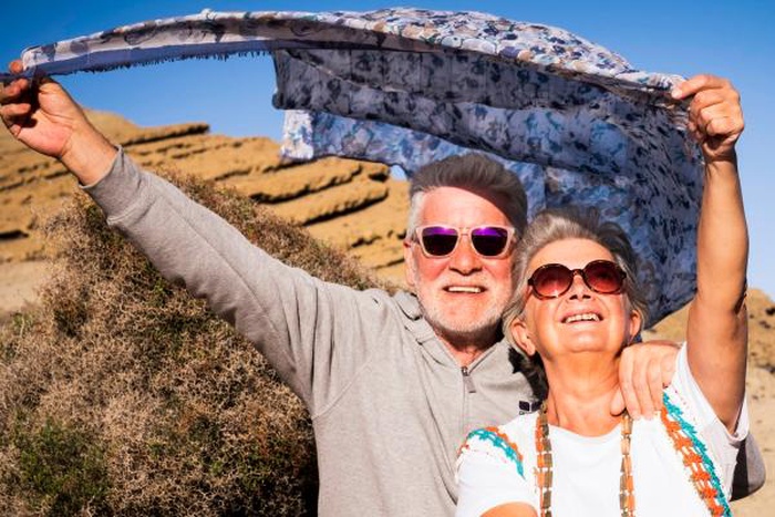 Senior couple with sunglasses smiling outdoors together