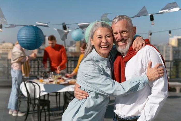 Joyful senior couple hugging at rooftop party