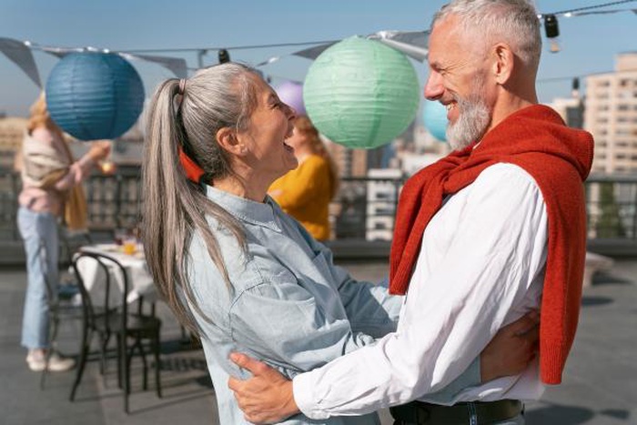 Senior couple laughing and dancing on a rooftop party date