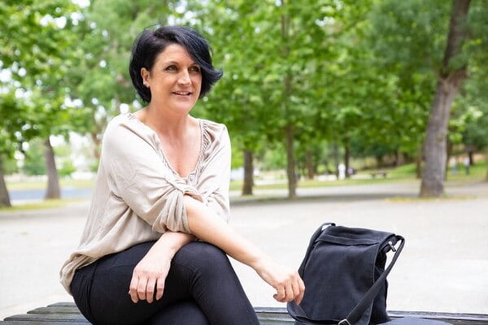 Content middle aged woman on bench in park