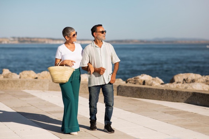 Mature man and woman strolling near ocean hand in hand