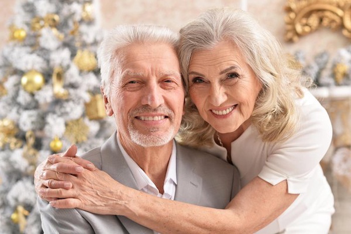 Portrait of hugging senior couple with blurred Christmas decorations