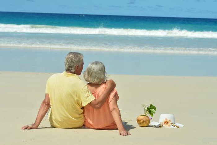 Senior couple sitting together on Florida beach enjoying retirement companionship