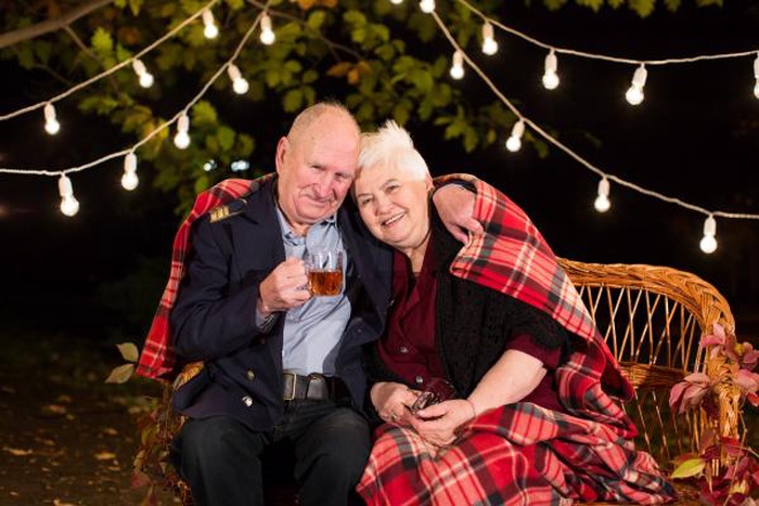 Elderly couple cozy night outdoors with string lights and plaid blanket