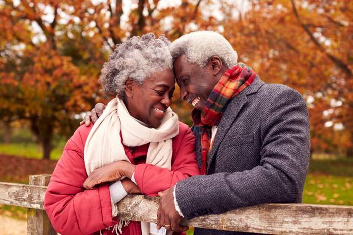 loving senior couple on walk through autumn countryside resting by gate