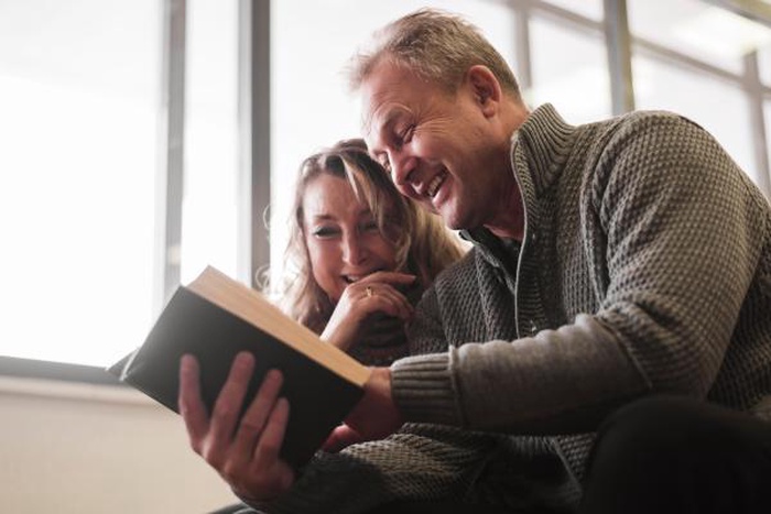 Senior couple laughing at book