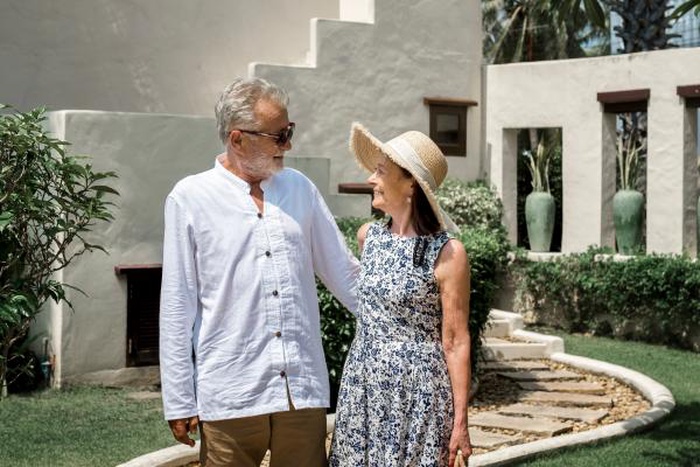 Romantic mature couple strolling hand‑in‑hand on holiday in sunny garden
