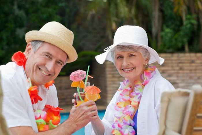 Senior couple toasting tropical poolside vacation cocktails