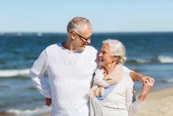 A happy elderly couple gazing lovingly at each other on a summer beach