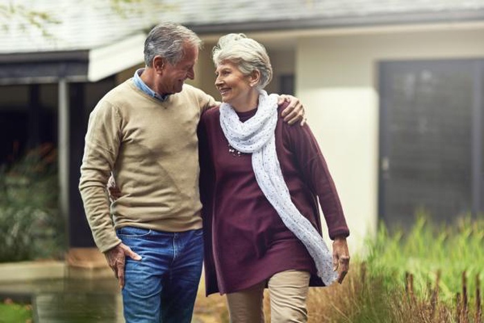senior man and woman on path together in their backyard at modern home