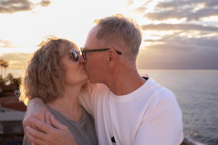 A beautiful mature and romantic couple hugs and kisses at sunset by the sea expressing love