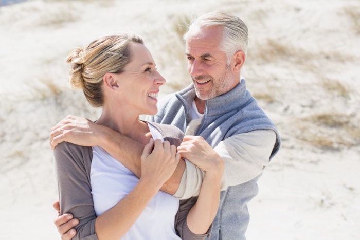 Happy hugging couple on the beach looking at each other