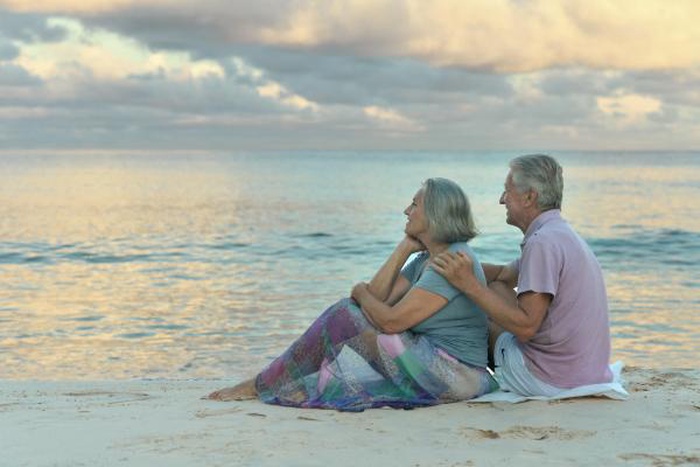 Mature senior couple relax on seaside beach at sunset, local over50 singles build companionship via US mature senior dating platform