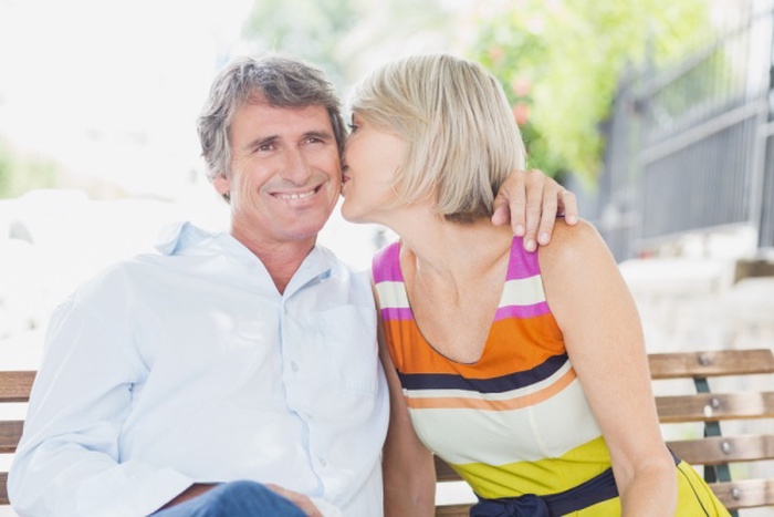 Blonde hair woman kissing man in park