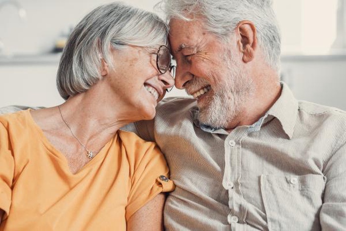 Loving senior couple smiling forehead-to-forehead at home