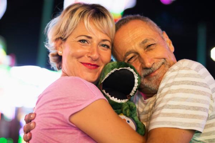 Senior couple hugging with carnival prize plush toy on a fun date
