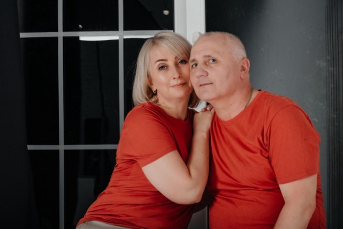 Husband and wife in orange t-shirts hug and kiss