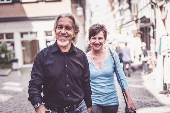 miling senior couple walking on street in city