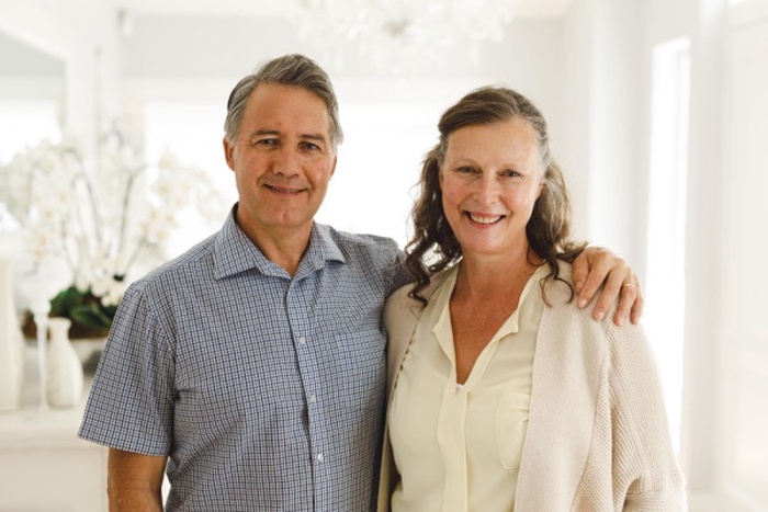 Portrait of happy senior caucasian couple in living room, embracing and smiling