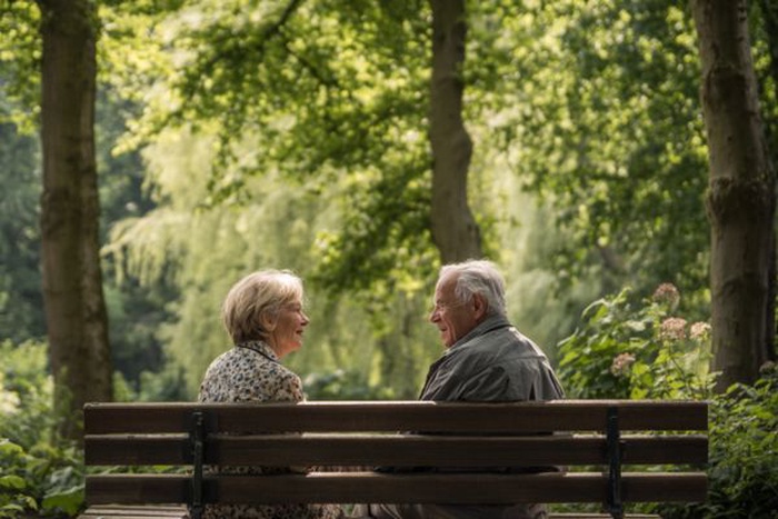 Couple senior de plus de 50 ans profitant d’un moment convivial sur un banc dans un parc calme à Jette.