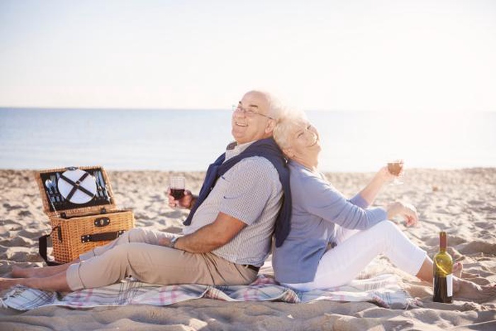 Loving senior couple enjoying a wine picnic on Whitstable beach, Kent &ndash; peaceful mature companionship by the British coast.