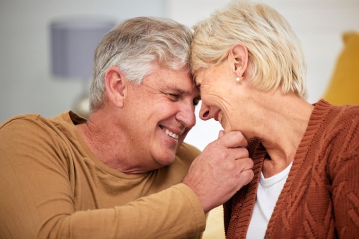 Forehead senior or happy couple smile in home for bond support or trust in a marriage commitment retirement love or face of mature man with a woman care or romance in a house together to relax