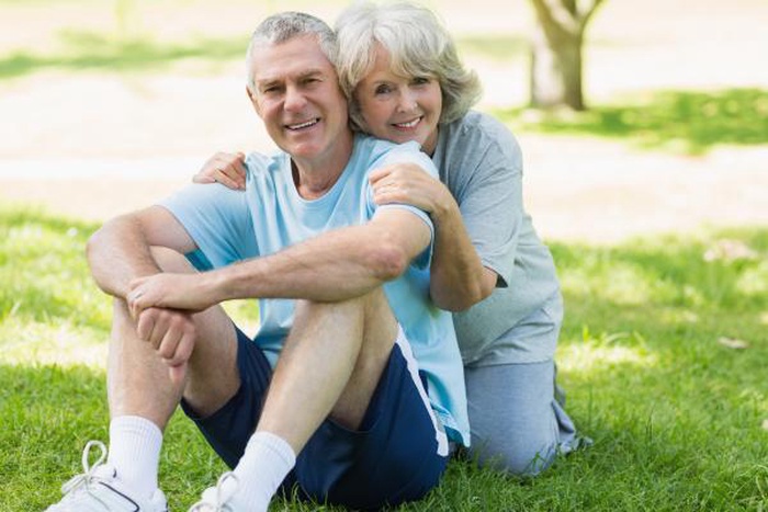 Smiling mature couple sitting on grass at park