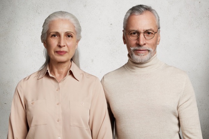 Mature couple posing against concrete wall