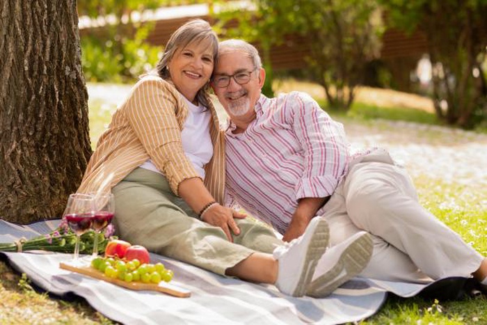 Happy mature couple relaxing on a picnic blanket in the park