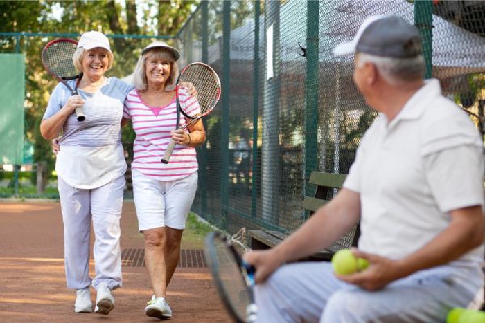 Seniors playing pickleball on an outdoor court, enjoying an active and social lifestyle over 50.