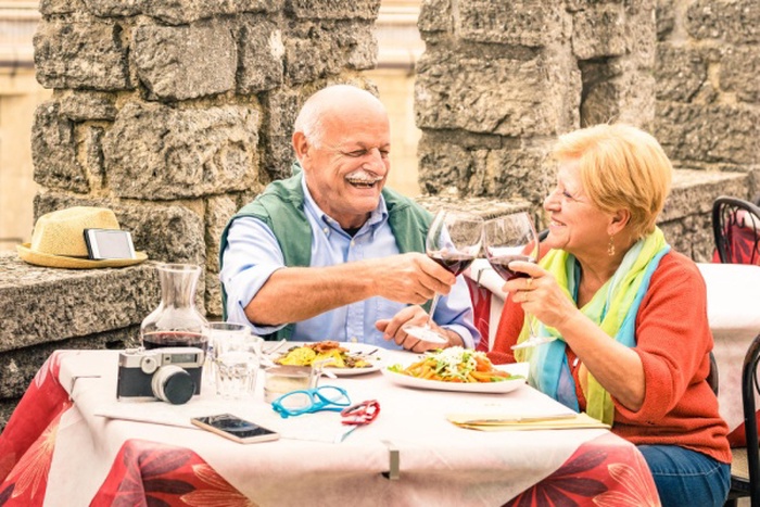 Senior couple toasting drinks while sitting on table at restaurant