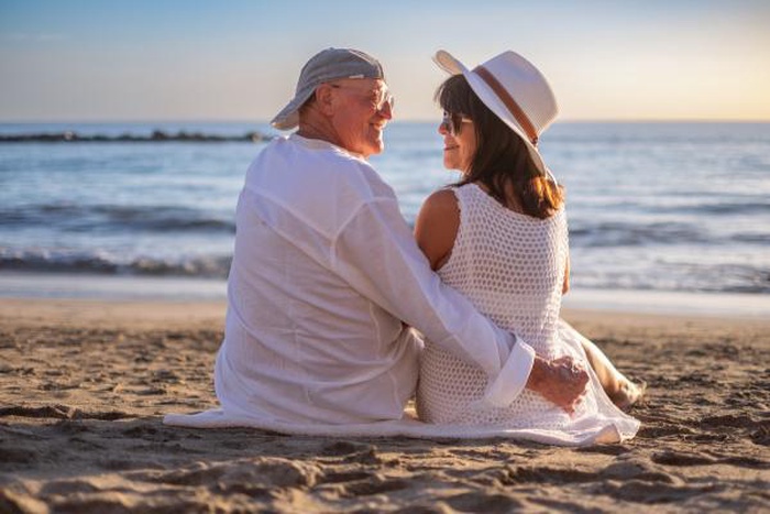 Back view of relaxed senior couple enjoying a sunny day at the beach smiling