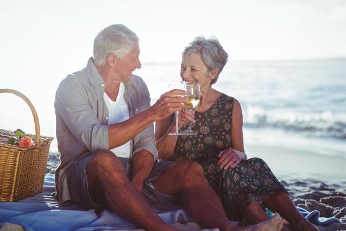 Cheerful aged pair have romantic seaside picnic for companionship, local 50+ mature senior dating scene