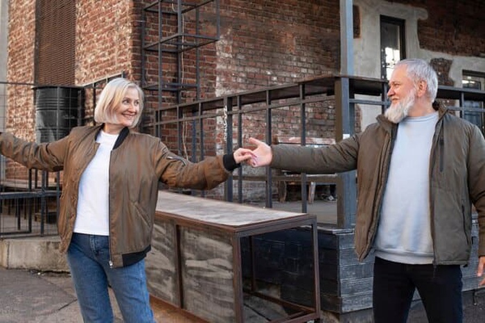Medium shot smiley senior couple dancing outdoors