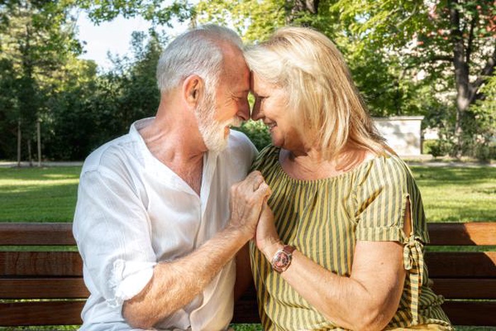 Cheerful aged pair share tender moment outdoors after matching on 50+ mature singles dating site