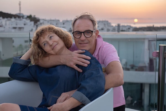 mature senior couple embraced on home terrace exchanging cuddles