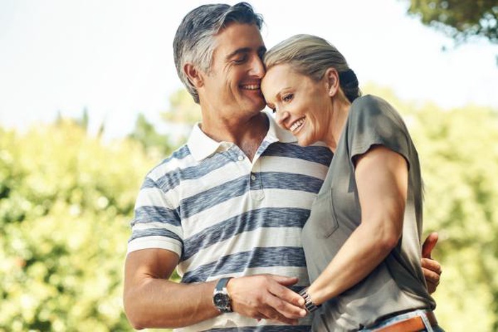 Loving mature couple embracing gently outdoors and smiling happily