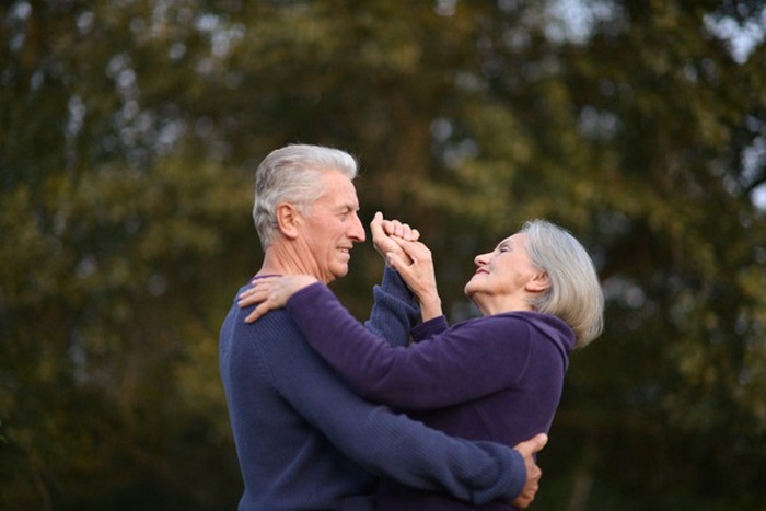 Happy senior couple dancing in summer park