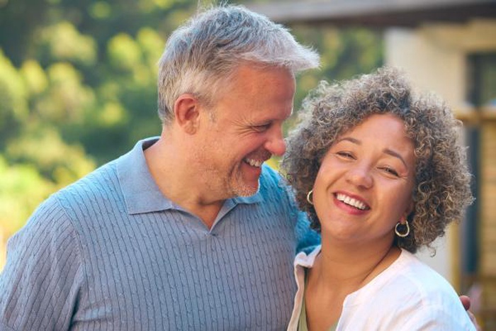 Cheerful diverse mature pair laughing side-by-side outdoors