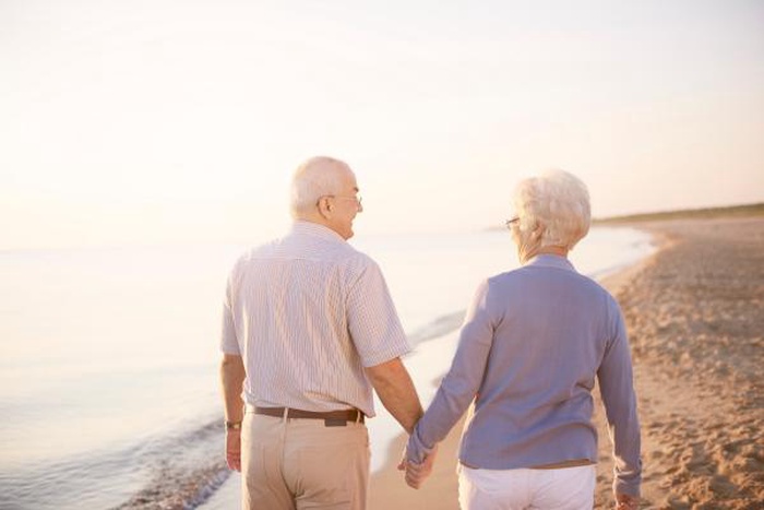 Senior couple holding hands while walking on the beach