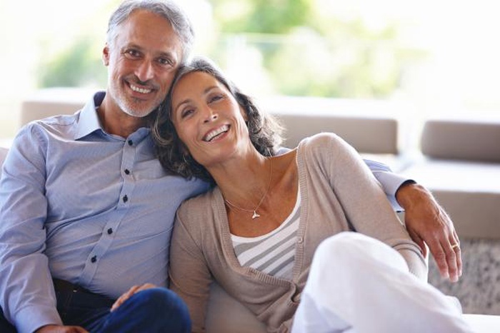 Happy middle-aged couple cuddling on the couch