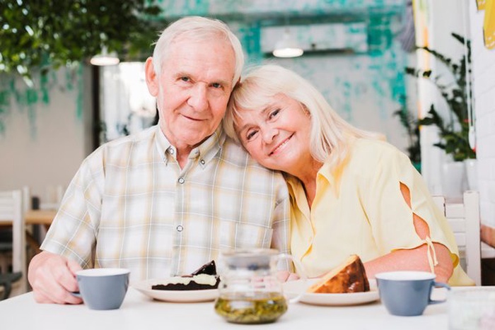 loving elderly couple drinking tea and eating cake