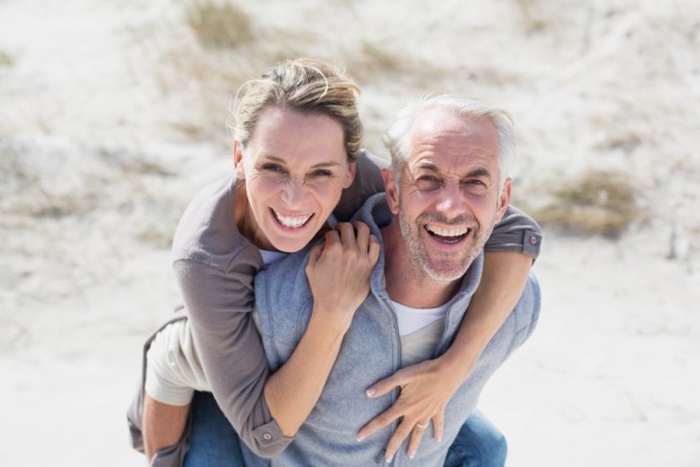  Laughing couple smiling at camera on the beach